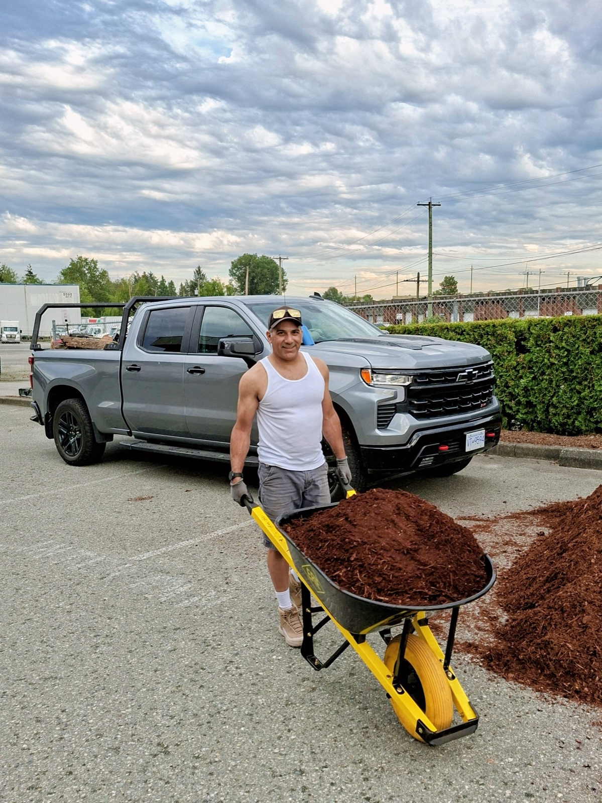 Danny Siggers hauling a wheelbarrow of mulch beside his work truck